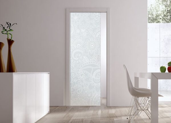 A modern, minimal room with light wood flooring features an ECLISSE Pocket Door Systems Classic Single Glass Door (10mm, patterned glass), white walls, a white sideboard, decorative vases, and a white dining table with chairs.