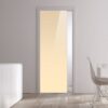 A modern, minimalistic room features an ECLISSE Pocket Door Systems - Classic Single Glass Doors 10mm (plain), white walls, wooden floor, a white sideboard with vases, and a white dining table with chair by a large window.
