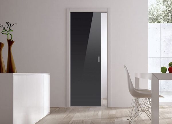 A modern, minimalistic room with an ECLISSE Pocket Door Systems - Classic Single Glass Doors 10mm (plain or patterned), white walls, wooden floor, a white cupboard left with two tall vases, and a white dining table and chair by the large window.