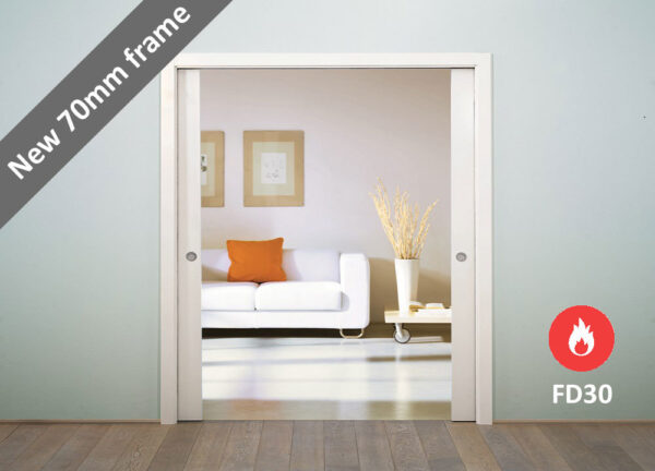 A modern sliding pocket door with a white frame opens to a living room with a white sofa, orange cushion, artwork, and vase. Banner shows "New 70mm frame" and FD30 symbol—ideal for ECLISSE Pocket Door System - Classic Double Fire-Rated.
