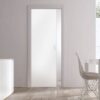An Eclisse Pocket Door System - CLASSIC SINGLE PLAIN GLASS SATIN 8mm 826X2040mm is partially open in a minimalist room with light walls, wooden flooring, a white chair, a white cupboard, and natural light streaming from the right window.