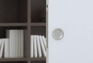 A close-up of a partially open ECLISSE Pocket Door featuring a Flush Pull Round Handle - Dia 57mm, with a blurred bookcase filled with books visible in the background.