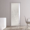 A modern dining area features an ECLISSE Pocket Door Systems - Classic Single Glass Doors 10mm Plain or Patterned. White furniture, wooden flooring, and natural light from a large window complete the elegant, minimalistic space.