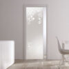 A modern interior with an ECLISSE Pocket Door System - Classic Single Glass Doors (10mm, patterned), white walls, light wood floor, white furniture, and tall decorative vases. Natural light streams through a window.