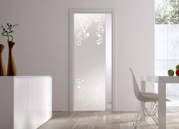 A modern interior with an ECLISSE Pocket Door System - Classic Single Glass Doors (10mm, patterned), white walls, light wood floor, white furniture, and tall decorative vases. Natural light streams through a window.