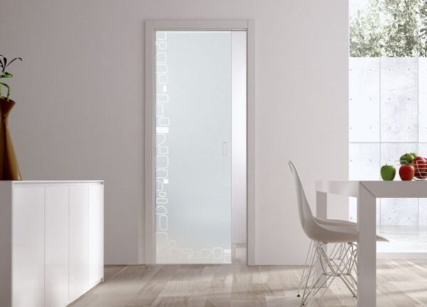 A modern, minimalistic room with an ECLISSE Pocket Door Systems - Classic Single Glass Doors 10mm Plain or Patterned featuring a geometric square pattern, white furniture, a white dining table with fruit, and light wooden flooring.