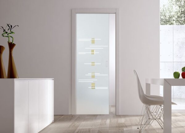 A modern interior with ECLISSE Pocket Door Systems Classic Single Glass Doors (10mm, patterned glass), white walls, light wood floors, a white cabinet, and a white dining table with a wire-frame chair.