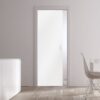 Minimalist room featuring white walls, a modern sideboard with vases, a white dining table and chair, and an ECLISSE Pocket Door Systems - Classic Single Glass Doors 10mm (plain or patterned). Natural light shines through the window on the right.