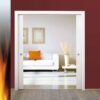 A modern living room with a white sofa and orange cushion is visible through open ECLISSE Pocket Door System - Classic Double Fire-Rated doors. Large flames rise nearby, their intensity contrasting with the calm interior.