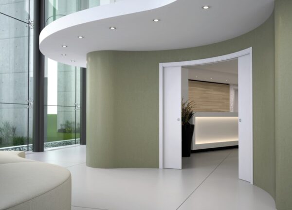 Modern office lobby with curved walls and Eclisse Pocket Door System - CURVED DOUBLE, recessed ceiling lights, large glass windows, and pocket doors leading to a bright reception area with wood panelling and indoor plants.