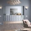 A modern living room with grey walls and light wood floors features a pink armchair, a large round mirror, a glass bubble chandelier, and the ECLISSE Pocket Door System - Classic Double Wiring-Ready as stylish sliding doors.