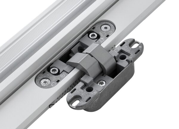 A close-up of a grey metal and plastic latch mechanism attached to a white ECLISSE Door System - Syntesis® Hinged Double frame, secured with multiple screws and featuring interlocking parts.