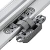 Close-up of a metal and plastic hinge on a white surface, part of the ECLISSE Door system - Syntesis® Hinged Single With Door, featuring screws and mounting plates for smooth operation.