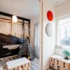 A bright children’s room features an ECLISSE Pocket Door System - Syntesis® Double for easy access, a teepee tent, table and stools, globe, colourful wall decor, a large window with yellow curtains, and an aeroplane mural on the back wall.