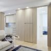 A modern flat features light wood panelling, an open kitchen with white cupboards, and a beige sofa. Hallway-to-bedroom access uses the ECLISSE Pocket Door System - Syntesis® Single for a seamless, minimalist look.