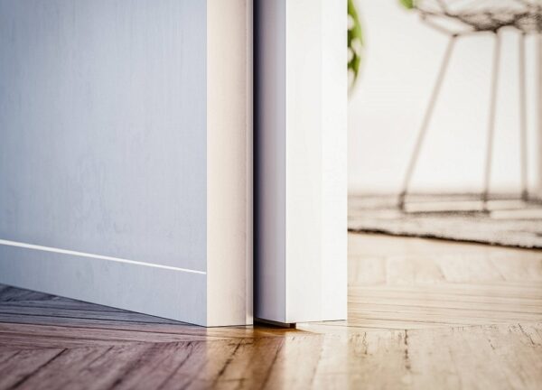 Close-up of the ECLISSE Pocket Door System - Syntesis® Single Wiring-Ready slightly open, sunlight casting shadows on a wooden floor. A blurred chair and plant in the background highlight the bright, modern interior.