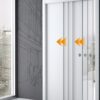 The ECLISSE Telescopic Synchronisation Kit is shown with sleek white pocket doors featuring two orange inward-pointing arrows, installed in a modern building with large windows and dark, line art-decorated walls.