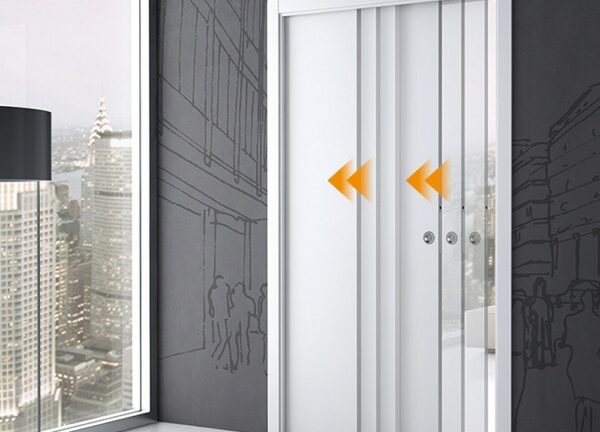 The ECLISSE Telescopic Synchronisation Kit is shown with sleek white pocket doors featuring two orange inward-pointing arrows, installed in a modern building with large windows and dark, line art-decorated walls.
