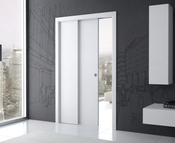 A modern interior with large windows and city views features an ECLISSE Pocket Door System - Telescopic Sliding Single set in a dark wall with city line art. Minimalist white shelves are mounted on the right.