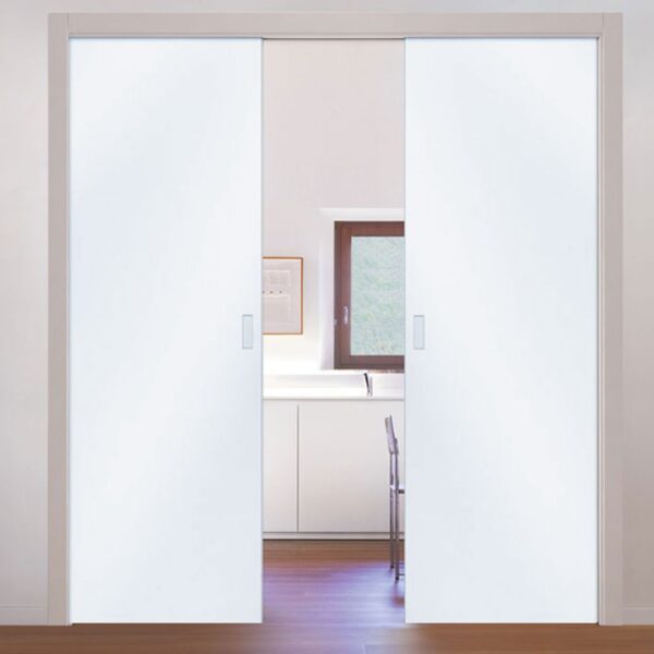 A pair of partially open ECLISSE Pocket Door System - Classic Double Glass doors reveal a modern kitchen with white cupboards, a window, and a chair. The area outside features wooden flooring.