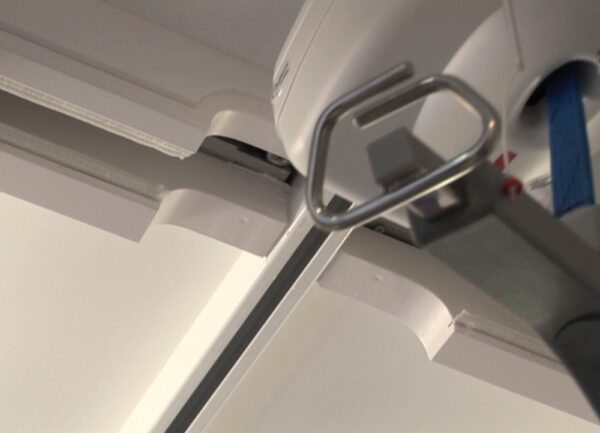Close-up view of a ceiling-mounted Classic Hoist Pocket Door System, showing the metal track and lifting mechanism, designed for patient mobility assistance in healthcare, similar to systems used in sliding or ECLISSE pocket doors.
