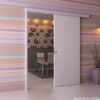 A modern room with pastel-striped wallpaper features an ECLISSE Wall Mounted Sliding Door Kit and Pelmet – 2m Track – Paris 2. Inside, a dining table, bold circular-patterned wallpaper, and a purple vase with branches near a wall light are visible.