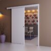 A modern room features a partially open ECLISSE Wall Mounted Sliding Door Kit, Pelmet and Door Post-2m Track-Paris 3, revealing a dining area. The space includes bold circular-patterned wallpaper and a purple vase with dried branches near a wall light.