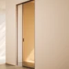 A modern interior showcases the ECLISSE VetroLuxe Aluminium Framed Glass Pocket Door, seamlessly set in a neutral wall. Sleek lines and soft natural light highlight this elegant, contemporary sliding door’s minimalist appeal.