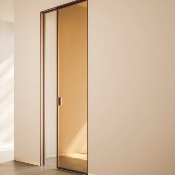 A modern interior showcases the ECLISSE VetroLuxe Aluminium Framed Glass Pocket Door, seamlessly set in a neutral wall. Sleek lines and soft natural light highlight this elegant, contemporary sliding door’s minimalist appeal.