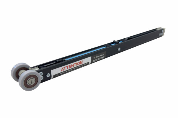 A close-up of a Cavity Sliders SofStop (Single & Double Action) black linear rail with two grey wheels on one end and an ATTENTION! warning label, appearing as a component for a sliding door or drawer system.